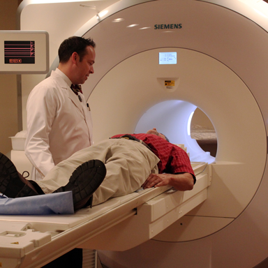 Technician helping a man into an fMRI machine